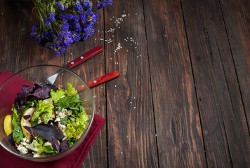 Top view of freshly harvested lettuce, lemon, blue cheese, pearand flowers on an old wood table