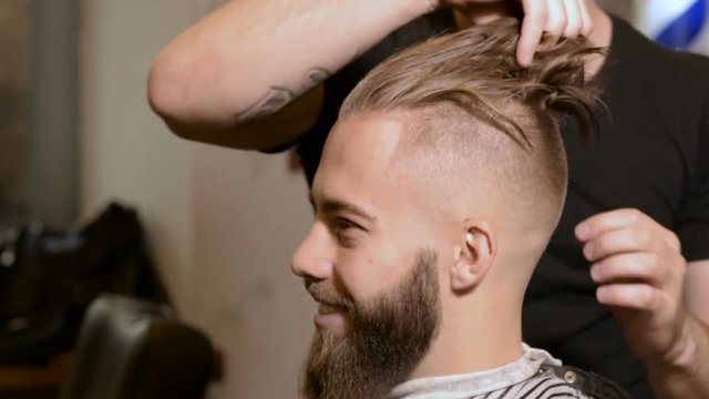 Professional barber styling hair of his client with hands