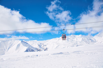 Fototapeta na wymiar Cable car on ski resort with blue sky background. Concept of snowdoard hobby. Place for rest and relax in snow season in mountains. Copy space for advertising or logo.