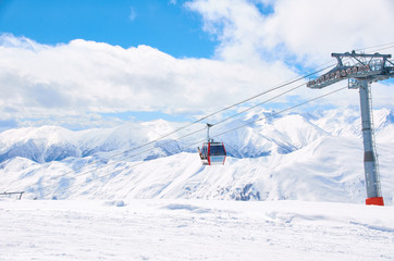 Cable car on ski resort with blue sky background. Concept of snowdoard hobby. Place for rest and relax in snow season in mountains. Copy space for advertising or logo.