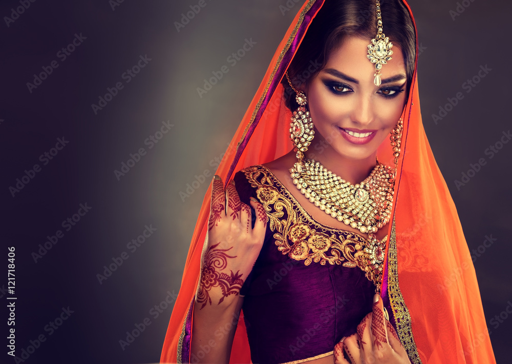 Wall mural Portrait of beautiful indian girl . Young hindu woman model with tatoo mehndi and kundan jewelry . Traditional Indian costume lehenga choli . 
