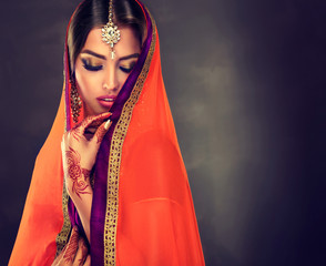 Portrait of beautiful indian girl . Young hindu woman model with tatoo mehndi and kundan jewelry ....