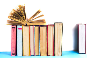 Obraz premium Open book, stack of colorful hardback books on light table. Back to school. Copy space for text