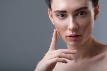 freckled woman with cream on her hands, grey background