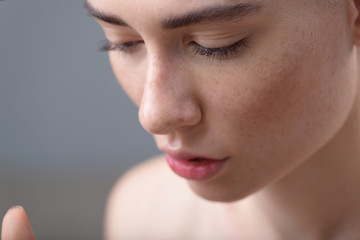 girl face with freckles on grey background and copy space