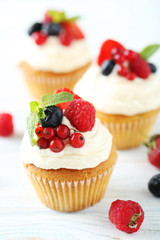 Tasty cupcakes with berries on white wooden table