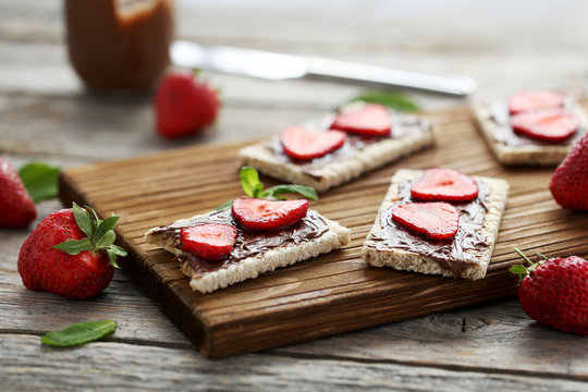 Breads with chocolate and strawberry on wooden table