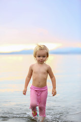 Fototapeta na wymiar Cute little blond girl walking on Ruakaka beach