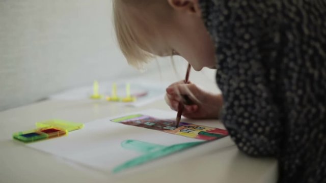 A small girl drawing a house with a pencil. Slow motion.
