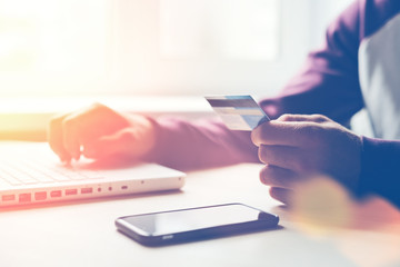 Man with bank card and laptop making online shopping (Intentional sun glare and lens flares)