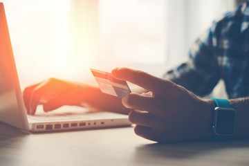 Man holding credit card and using laptop. Online shopping (Intentional sun glare and lens flares)