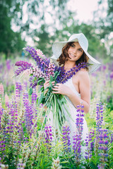 Girl with a bouquet of lupine on the field