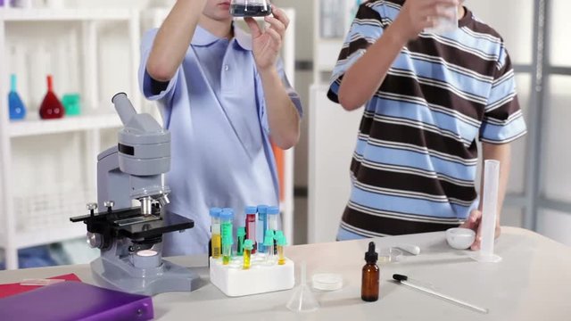 Two young students with classroom laboratory paraphernalia working on a science project.