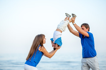Men and woman shake a boy on the sea and have fun on a bright sunny day