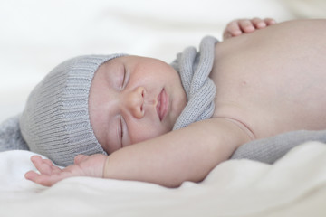 newborn sleeping in a white background with hat and scarf