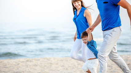 Man woman and child run on the beach near the ocean and feel happy