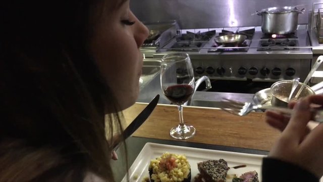 Woman eating a tuna with a industrial kitchen on background