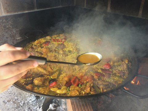 cocinero con paella valenciana a fuego cocinada