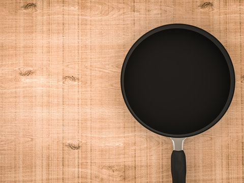 empty black pan on wooden table