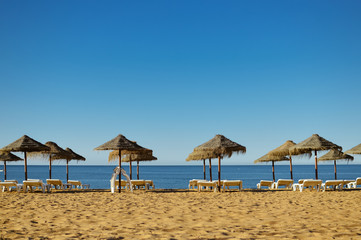 Blue sky and straw umbrella on a beautiful tropical beach background