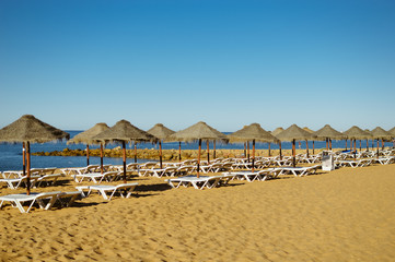 Blue sky and straw umbrella on a beautiful tropical beach background