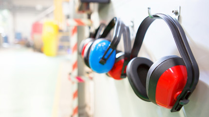 Row of Ear Defenders hung up in a factory with copy space - obrazy, fototapety, plakaty