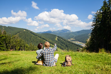 Travelling couple sitting on the alpine meadow