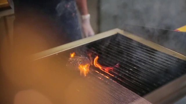 cook frying the meat on the grill.