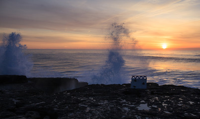 Fototapeta premium Romantic bench on Ericeira seaside at sunset, Portugal