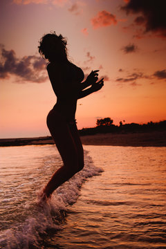 Girl jumping in the waves at sunset