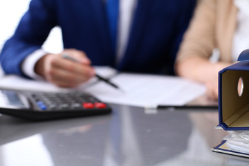 Binders with papers are waiting to be processed with businessman and secretary back in blur. Internal Revenue Service inspector checking financial document.