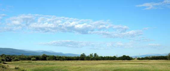 Blue sky and cumulus clouds over the Eastern Sayan Mountains and Mount MunKu-Sardyk. Photo partially tinted.