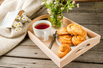 Cozy breakfast in spring or early autumn tea, freshly baked scones and bouquet of field's daisy and...