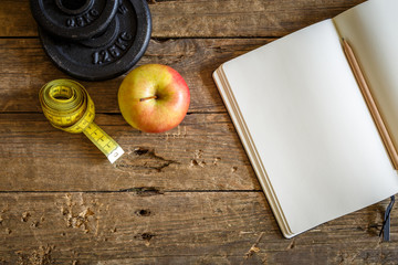 Apfel, Maßband und Trainingstagebuch auf rustikalen Holztisch