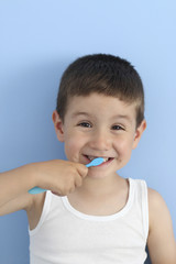 happy child brushing his teeth in a blue background