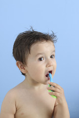 happy baby brushing his teeth with a toothbrush in a blue background