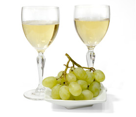 two glasses of sparkling white wine. green grapes on a white plate. isolated on white background