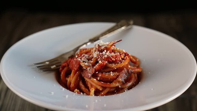 bucatini with amatriciana sauce in the dish in movement