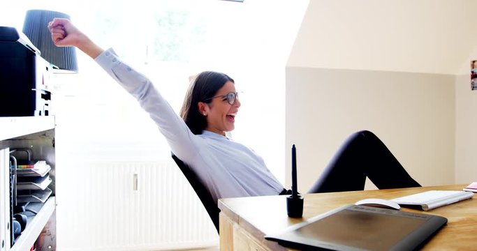 Business woman sitting at desk cheering at computer, entrepreneur concept