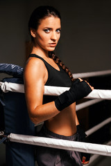 Fototapeta na wymiar Young fitness beautiful brunette girl with boxing gloves on the ring
