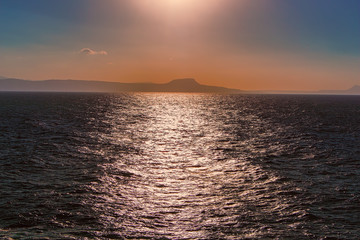 Obraz premium Dark blue sea with island on horizon in the evening, sunset.