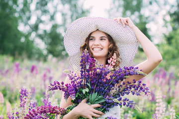 Girl with a bouquet of lupine on the field