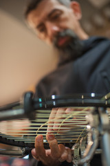 Stringing Machine. Close up of tennis stringer hands doing racket stringing in his workshop