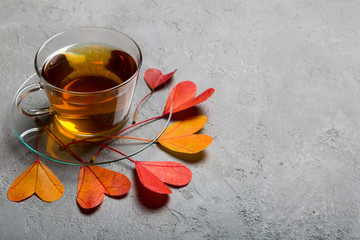 Cup of tea with colorful heart leaves on concrete background. Copy space.
