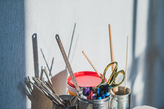 Stationery in metal cans casting shadows on grey wall
