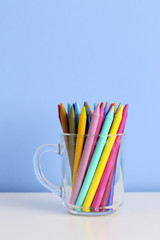 vase of glass with colorful crayons of different colors in a blue background