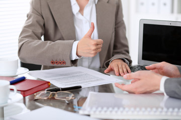 Group of business people or lawyers at meeting  discussing contract papers. Woman showing thumb up