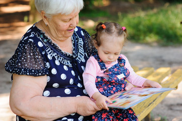 Grandmother and granddaughter reading the book in the park
