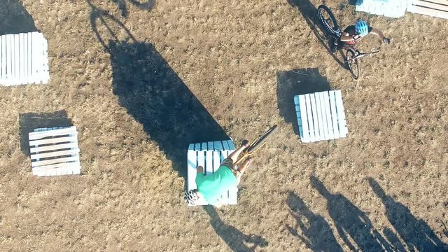 Сyclists doing jump MTB tricks in bicycle 4k aerial top view video. Mountain bike trial rider in park. Extreme sport lifestyle show