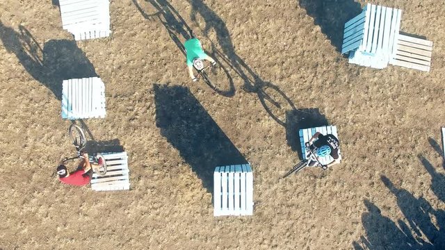 Сyclists doing jump MTB tricks in bicycle 4k aerial top view video. Mountain bike trial rider in park. Extreme sport lifestyle show